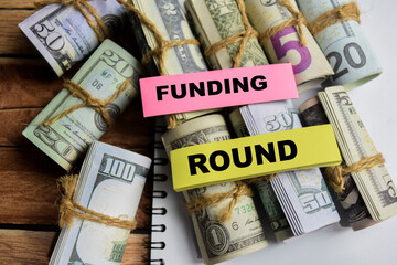 Concept Funding Round on sticky notes on a wooden table with dollar bills