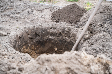 A round hole dug in the ground and a shovel in it