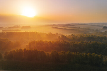 Obraz premium Foggy autumn forest and fields with village in distance