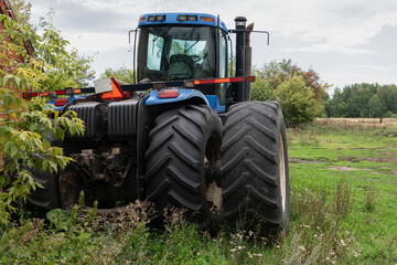 Obraz premium A broken huge agricultural tractor in the countryside on a farm awaiting repair