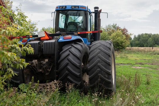 A broken huge agricultural tractor in the countryside on a farm awaiting repair