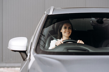 Businesswoman driving modern car and smiling at daytime