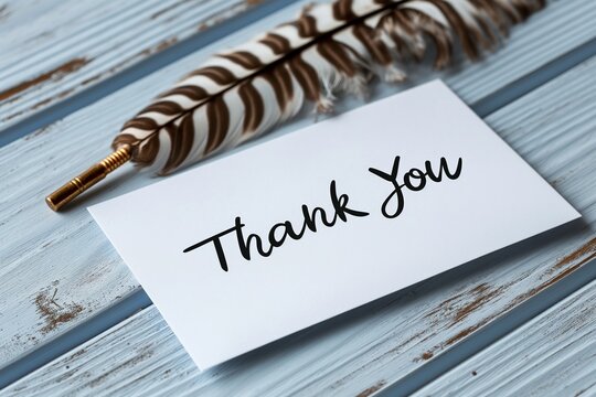 Thank you card with feather pen on wooden surface
