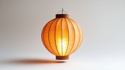 Illuminated orange paper lantern casting soft shadow against a neutral background in studio setting for home decor