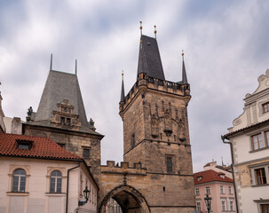 Fototapeta premium Lesser Town Bridge Towers on Charles Bridge in Prague, featuring gothic architecture and historic stonework under a cloudy sky.