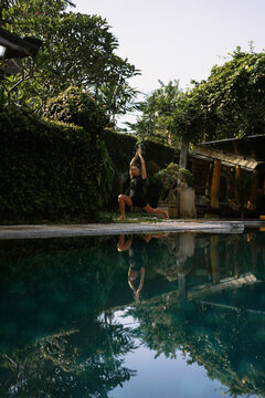 Young woman practising yoga at the poolside