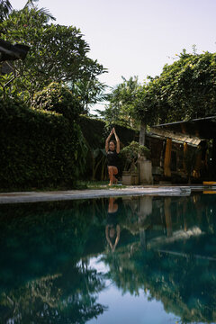 Young woman practising yoga at the poolside