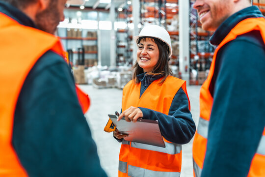 Warehouse workers smiling and discussing logistics with digital tablet and laser scanner