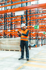 Fototapeta premium Warehouse worker scanning packages with barcode scanner in logistics center