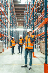 Warehouse manager using smartphone, coordinating logistics operations with his team