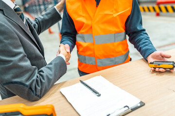 Manager shaking hands with warehouse worker after signing contract