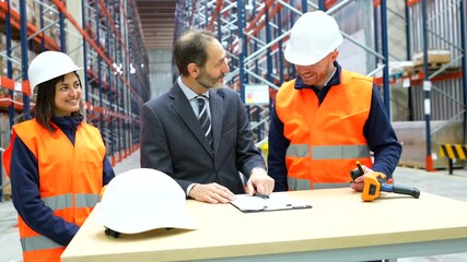 Professional logistics manager and warehouse worker finalizing business agreement through handshake, celebrating successful partnership in industrial storage facility