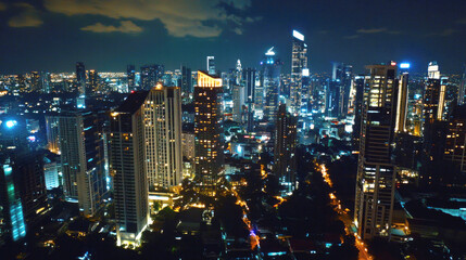 Fototapeta premium Captivating nighttime aerial cityscape with illuminated skyscrapers and cloudy sky