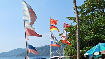 National flags waving at Patong Beach, Phuket, with a clear view of the coastline - Powered by Adobe