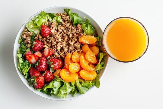 Healthy salad bowl with fruit and granola.  Fresh greens topped with crunchy granola, juicy strawberries, and segments of orange. A refreshing side of orange juice