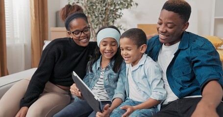 In a cozy room of their new home, the family explores furniture ideas online. The siblings grin as they point to their favorite decorations.