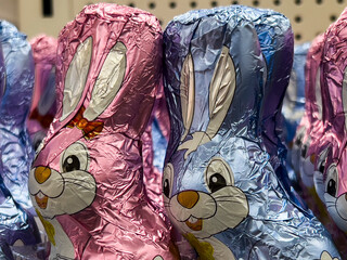 Chocolates in the shape of a cute Easter bunny wrapped in gilded paper are on the market shelf.