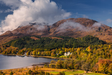 Fototapeta premium Golden autumn hues surround the Glenfinnan Viaduct, as misty hills and serene lochs create a magical Highland scene. A perfect blend of history and nature in Scotland’s fall splendor.