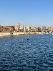 Fototapeta premium View of Esna city with vendors in their rowing boat near the Esna Lock on the River Nile, Egypt