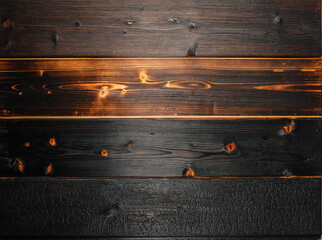 Close-up of horizontal burned wood planks with visible grain, knots, and charring, showcasing...
