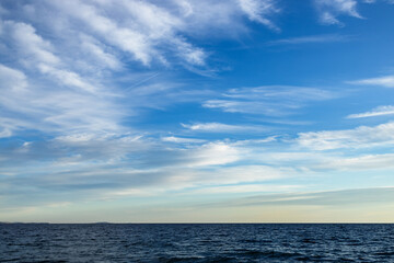 Dark blue waves of the Gulf of Athens. A pattern of fluffy and feathery white clouds in a bright...