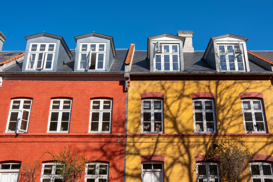Red and yellow facades with classic dormer windows in Indre By, Copenhagen, captured in clean spring light, perfect for lifestyle and architectural themes.