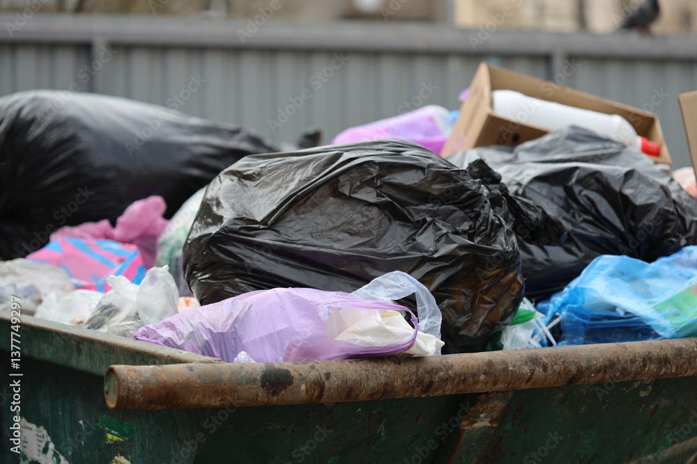 Poster a large green dumpster filled to the brim with various types of garbage, great for depicting polluti