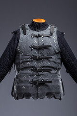 Gray Medieval Brigandine Armor with Leather Straps. This gray brigandine features overlapping metal plates riveted to a fabric base, secured with leather straps.