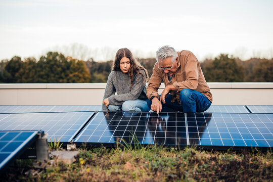 Grandfather and granddaughter discussing solar panels outdoors