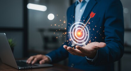 Achieving business success: Man holding glowing target with laptop in workspace