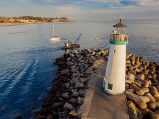 Walton Lighthouse in Santa Cruz, California, USA. People walk along the breakwater, enjoying the...