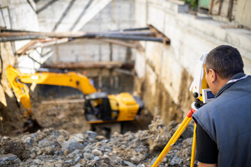 Fototapeta premium Construction worker surveying site with machinery in background at early morning light