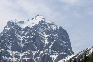 Snowy mountain peak under light clouds in Banff National Park, with soft light highlighting ridges and natural stone texture