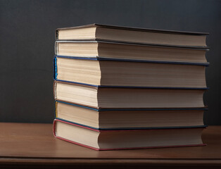 A stack of books on a green background, on a carved table. 