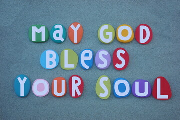 May God bless your soul, creative message composed with multi colored hand painted stone letters over green sand