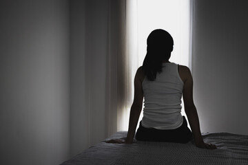 Silhouette of Young women sitting in dark room feeling pain with life problem. suffering from husband violence, Stop violence against and sexual abuse women, domestic violence, anti human trafficking.