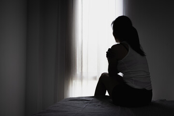Silhouette of Young women sitting in dark room feeling pain with life problem. suffering from...