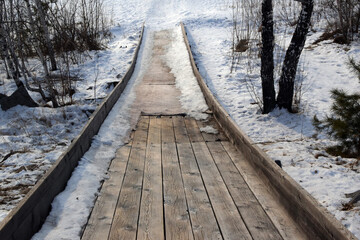 Steep descent from wooden snow slide from top to bottom. Snow slide has melted.
