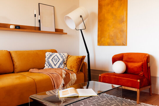 Stylish modern living room interior. Elegant floor lamp and soft bright sofa with armchair. Open book on glass coffee table. Natural colors and materials.