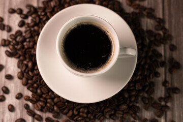 A cup of coffee on coffee beans. Cup of coffee on dark background top view