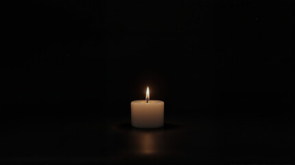 "A minimalist stock photo featuring a single burning candle against a solid black background. The candle is white or cream-colored, with a soft, warm flame creating a gentle glow.