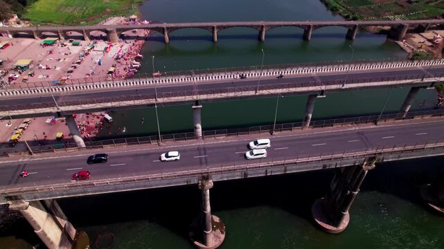 vehicles moving on Bridge with narmada river and farming lands at Jotpur, Jabalpur, madhya pradesh, india. day time, push back, tilt up, drone shot, 4k.