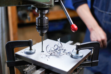Close-up of metal drilling with drill press in workshop setting