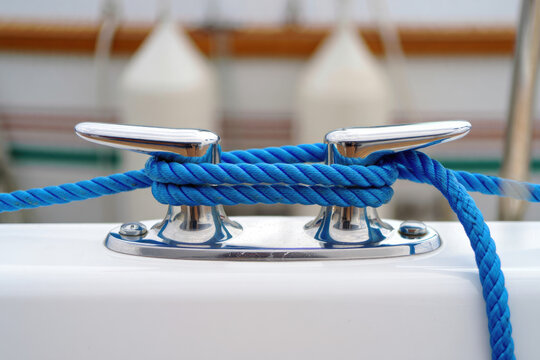 Blue rope knot tied on shiny boat cleat for secure mooring