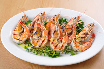 Grilled shrimp garnished with fresh herbs on a white plate