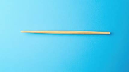 A minimalist composition featuring a single wooden toothpick positioned diagonally on a vibrant blue background. ideal for culinary or product presentations