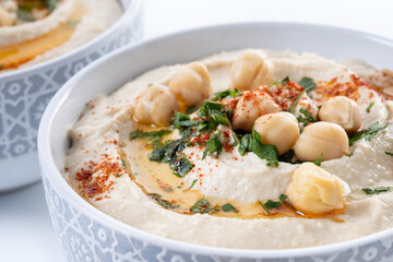 Chickpea hummus with olive oil, parsley and paprika in bowl isolated on white background. Close up