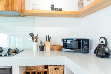 Simple modern kitchen with white counter and wooden top and kitchenware in the cabinets.