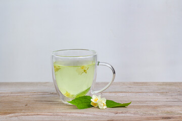 Fresh herbal tea with jasmine. glass cup on wooden table