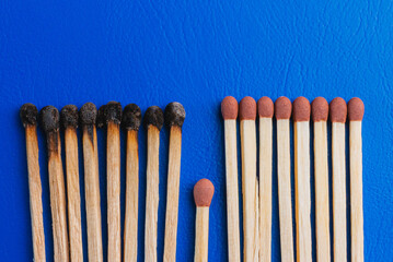Group of burnt out and unused match sticks on blue background. Save a community concept.